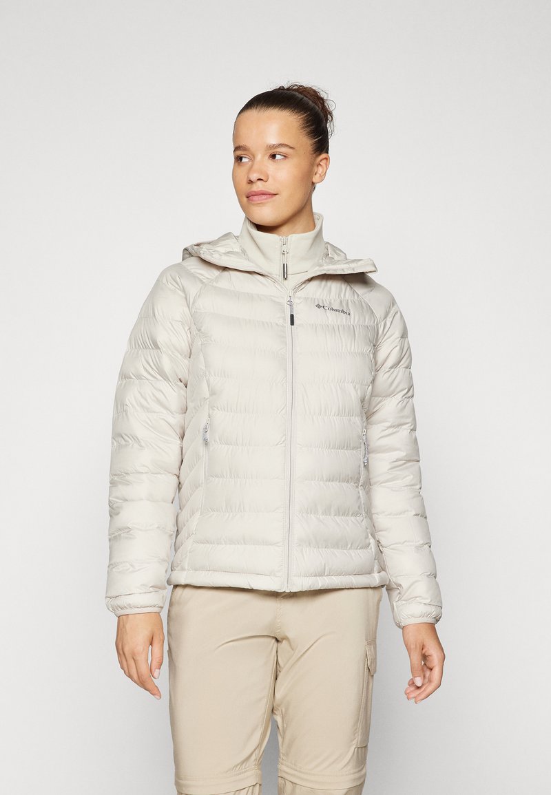 Lett pufferjakke i myk beige med horisontal quilt, full glidelås, påsydde hette og to glidelåslommer på sidene.