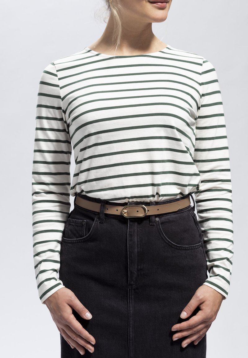 Valkoinen ja vihreä raidallinen pitkähihaisen t-paita, joka on valmistettu puuvillasta, yhdistettynä korkeavyötäröiseen mustaan farkkuhameeseen ja ruskeaan vyöhön, jossa on kultainen solki.