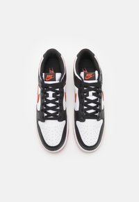 Baskets Nike avec une tige en cuir noir, des panneaux en cuir blanc et des accents orange. Design à lacets avec un bout perforé et un col rembourré.