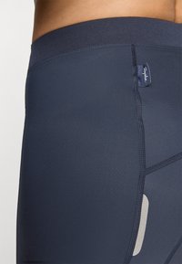 Námořnické sportovní šortky vyrobené z elastického materiálu, s plochými švy, vysokým pasem a reflexním detailem po straně.