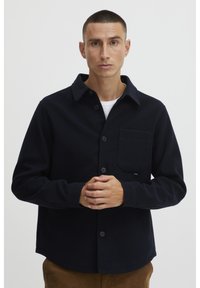 Navy button-up shirt in a soft material, features a spread collar, chest pocket, and long sleeves with button cuffs.