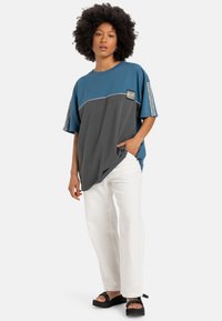 Kleurgeblokkeerd T-shirt in teal en grijze katoen, met een ronde hals en korte mouwen. Bevat een klein logopatch en geaccentueerde patronen op de mouwen.