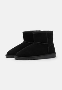 Zwarte enkellaarsjes van suede, met een ronde neus, korte schacht en een platte rubberen zool met gestructureerde details.