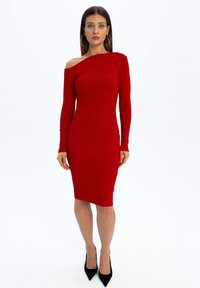 Czerwona, prążkowana sukienka bodycon, z odkrytymi ramionami, długimi rękawami, długości do kolan. Noszona z czarnymi szpilkami, gładka faktura, dopasowany krój.