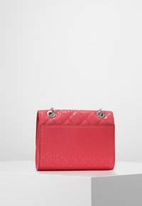 Růžová prošívaná taška s reliéfním vzorem loga, lesklým povrchem a stříbrným kováním. Má strukturovaný tvar a horní klopu na zavírání.