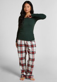 Bosgroene longsleeve top gecombineerd met witte, rode en zwarte geruite pyjamabroek. Katoenen stof, ontspannen pasvorm, met een casual, comfortabele stijl.