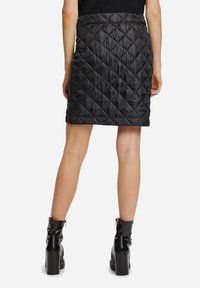Svart kviltad kjol med ett diamantmönster, som har en lätt utsvängd fåll och en slät, glansig nylonstruktur. Känns perfekt ihop med svarta högklackade stövlar.
