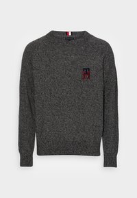 Grauer Strickpullover mit gerippten Bündchen und Kragen. Verfügt über ein kleines, in Rot und Marineblau gesticktes Logo auf der Brust.