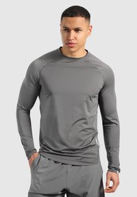 Langärmliges Sportshirt in Grau, aus glattem, leichtem Stoff mit schmaler Passform; verfügt über Nähte entlang der Schulternähte und ein Logodesign.