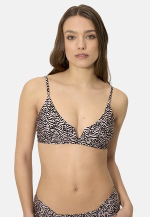 Mujer con un top de bikini de estampado rosa y negro y pantalones a juego, posando contra un fondo claro y liso.