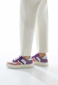 Les baskets présentent une base en cuir blanc avec des panneaux en suède violet et rose, une semelle en caoutchouc texturée et des lacets ronds. Design minimaliste avec des touches d'accent.