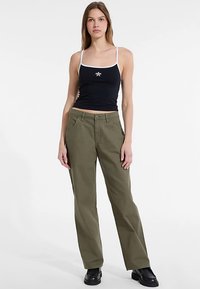 Must tanki valgete rihmade ja tähe detailiga, kombineeritud oliivroheliste laia säärega pükstega. Komplekt on mugava ja lõdvestunud istuvusega.