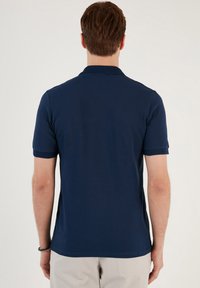 Námořnická modrá polo tričko s krátkými rukávy, strukturovaným límcem a manžetami, přiléhavý design, vyrobené z hladké tkaniny, bez viditelných log a vzorů.