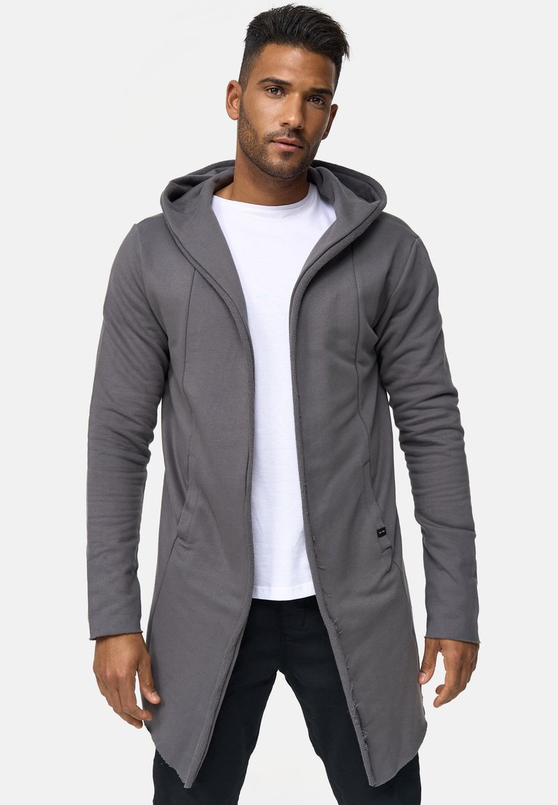 Grijze hoodie lange cardigan gemaakt van zachte stof, met een opening aan de voorkant, zijzakken en een casual ontwerp, gedragen over een wit shirt.