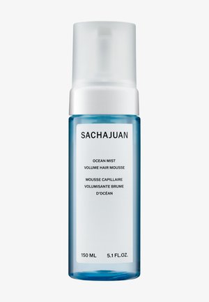 Heldere blauwe fles met een witte pomp, gelabeld "Sachajuan Ocean Mist Volume Haarmousse," 150 ml. Eenvoudig, modern ontwerp met minimale tekst.