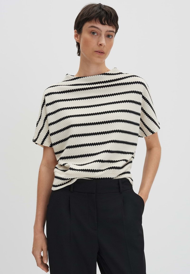 Maglione corto lavorato a maglia con righe zigzag bianche e nere. Vestibilità rilassata, maniche corte, scollatura rotonda, tessuto testurizzato. Abbina a pantaloni neri.