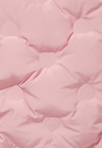 Cuscino imbottito rosa con una superficie morbida, decorato con motivi a forma di cuore delicatamente impresso per un tocco di dettaglio in più.