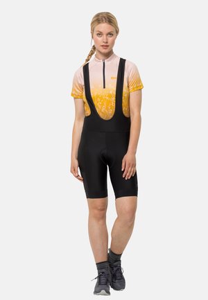 Tenue de vélo avec un maillot à manches courtes en dégradé rose et jaune orné de fleurs, associé à un cuissard noir et des chaussures grises.