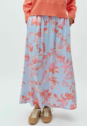 Květinová maxi sukně v světle modré barvě s korálovými a růžovými botanickými vzory. Elastický pas, volný střih. Kombinováno s hnědými teniskami.
