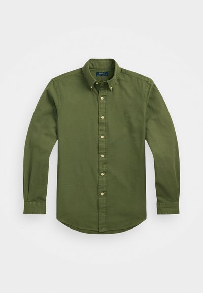 Camisa verde de manga longa abotoada, feita de algodão, com um colarinho pontiagudo, frente abotoada e um pequeno logótipo bordado no peito.