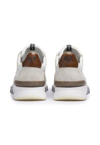Weißer Sneaker mit Wildleder- und Lederakzenten, ausgestattet mit einer braunen Ferse, strukturierten Einsätzen und einer dicken, grauen Sohle mit gelbem Unterbau.
