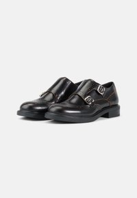 Zwarte leren schoenen met dubbele gespbanden, met geperforeerde details langs de naden en een gestructureerde zwarte zool.