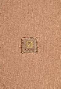 Tessuto color pesca con una superficie liscia, caratterizzato da un badge quadrato cucito nell'angolo, che mostra il logo "GABBANO" in oro.