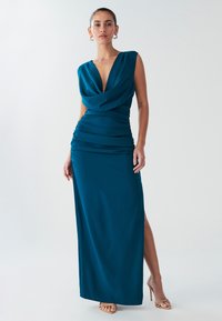 Türkiissinine, varrukateta maksikleit sügava V-kaeluse ja kokkupandud vöökohaga. Omab külje kokkutõmbeid ja reie kõrgust lõhet, valmistatud siledast kangast.