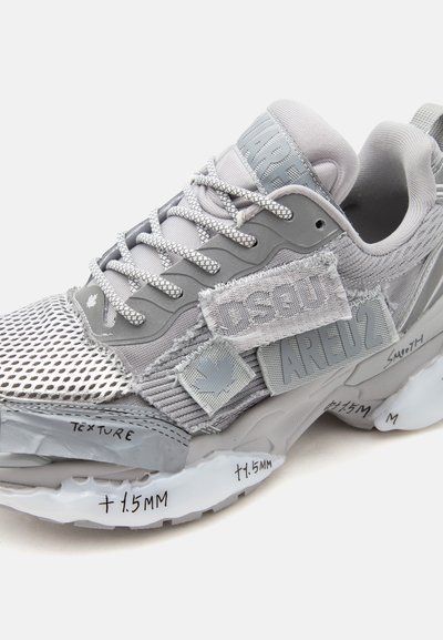 Γκρι αθλητικό παπούτσι με πλέγμα, υφασμάτινες λεπτομέρειες με υφή, κορδόνια με λογότυπο και χειρόγραφες μετρήσεις στη σόλα και τις λεπτομέρειες του μεσαίου μέρους.