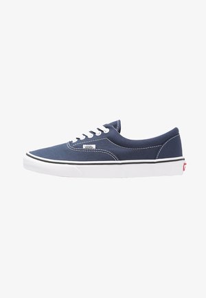 Baskets en toile bleu marine avec lacets blancs, semelle en caoutchouc et rayure noire. Comprend une petite étiquette de logo sur le côté et un revêtement intérieur blanc.