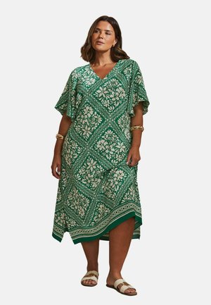 Groene jurk met bloemenpatroon, korte mouwen, V-hals, asymmetrische zoom en lichte stof. Accentueert met een contrasterende bies.