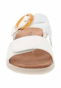 Sandal bianca con un grande accento circolare arancione, cinturini testurizzati e una soletta marrone morbida. Design leggero con suola piatta.