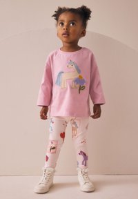 Light pink long-sleeve shirt with unicorn and flower embroidery, paired with white leggings featuring colorful patterns and lace-trimmed cuffs.