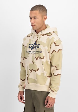 Tan camo hoodie with brown patterns, drawstring hood, front pocket, and front logo. Soft fabric with ribbed cuffs and hem.