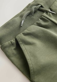 Oliven grønne bomulds joggere med ribbet talje, snøre lukning og sidelommer. Har en blød tekstur og et afslappet design.