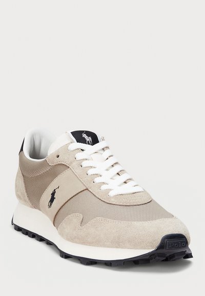 Baskets beige et crème en suède et mesh, avec des accents texturés, des lacets blancs, et une semelle en caoutchouc noire avec un logo.