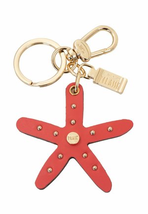 Portachiavi dorato con un charm in pelle a forma di stella marina rossa, decorato con piccoli rivetti dorati e una targhetta in oro incisa con il nome del marchio.