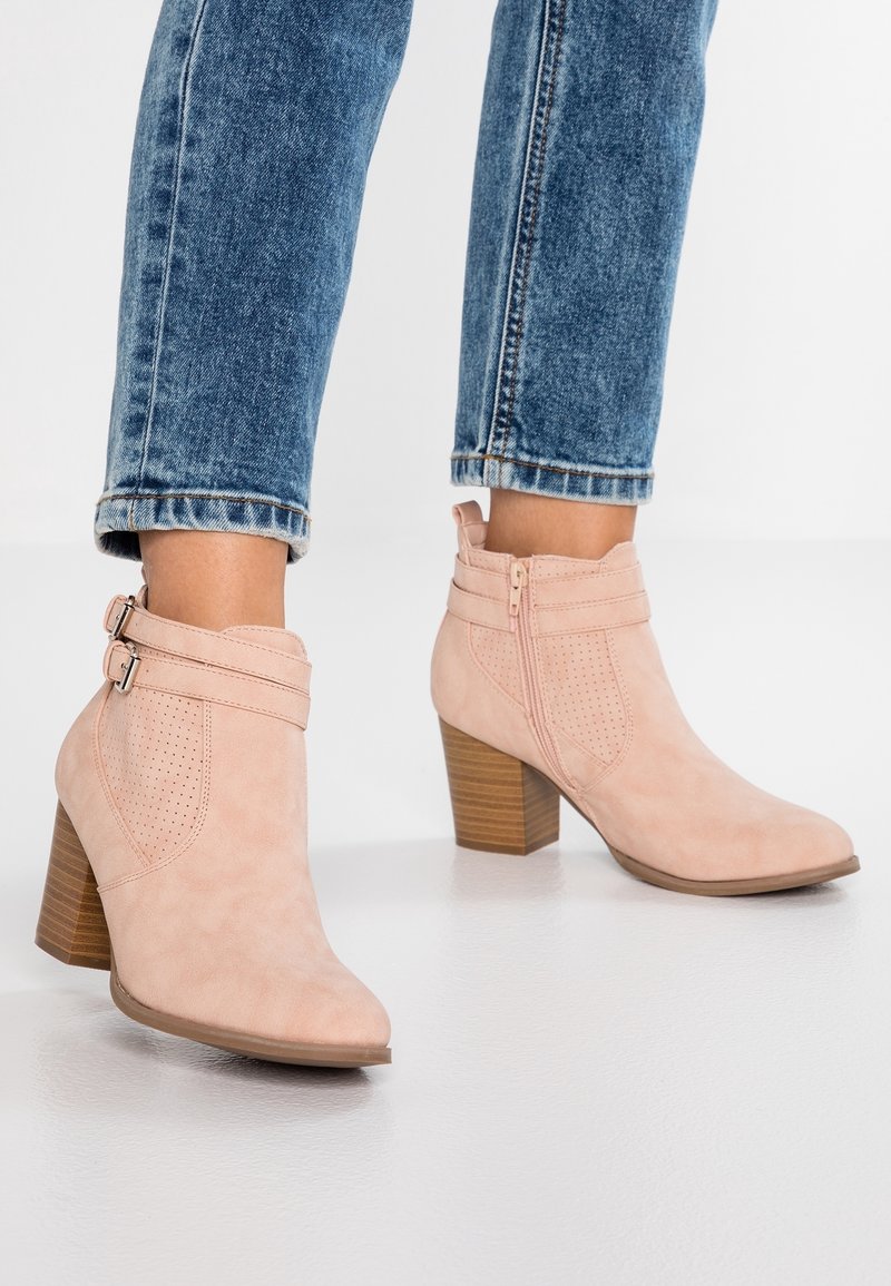 Bottines en suede rose à bout pointu, dotées de deux brides à boucle, d'un design perforé et d'un talon en bois empilé.