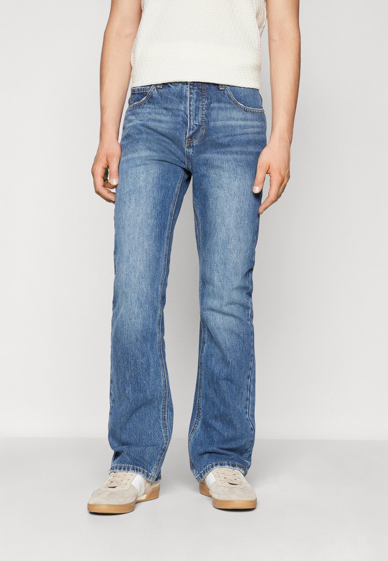 Lys blå denimjeans med rett benpassform, med kontraststing og femlommers design, kombinert med beige joggesko.