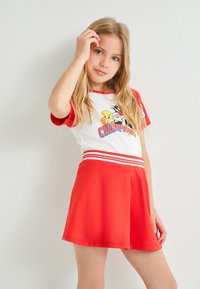 Conjunto rojo y blanco que incluye una camiseta de manga corta con un gráfico de dibujos animados y una falda roja acampanada con rayas blancas en la cintura.