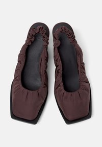 Pair of dark brown fabric slip-on shoes with ruched edges and square toes, displayed from above on a light background.