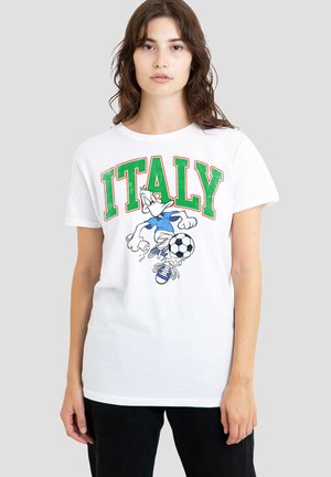 Junge Frau trägt ein weißes T-Shirt mit "ITALY" in grünen Buchstaben und einer Cartoon-Ente, die Fußball spielt und einen schwarz-weißen Ball hält.