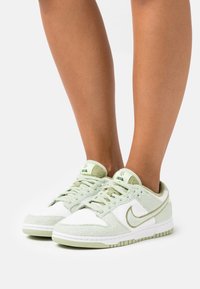 Baskets Nike vert clair présentant un mélange de tissu texturé et de matériau lisse, avec des accents blancs et des semelles en caoutchouc vert.