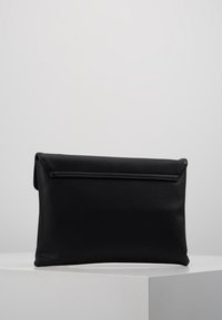 Svart clutchväska i mjukt material, med ett vikbart lock och rena linjer. Designen är minimalistisk utan synlig hårdvara.