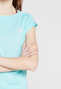 T-shirt de sport à manches courtes bleu clair en tissu lisse, doté d'un logo subtil sur la poitrine et de manches retroussées.