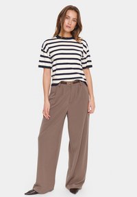 Pull rayé crème et marine, associé à un pantalon long taille haute marron. Mélange de laine avec une coupe ample et un design à l'avant plat.