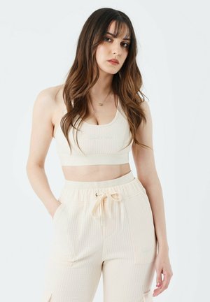 Lichtbeige cropped sportsbra en bijpassende joggers met een getextureerd wafelpatroon, voorzien van een elastische tailleband en trekkoorddetail.