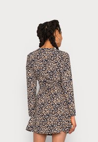 Vestido de mangas longas em azul-marinho com padrão animal bege. Forma ajustada com saia rodada. Tecido macio e texturizado que realça a visibilidade do padrão.