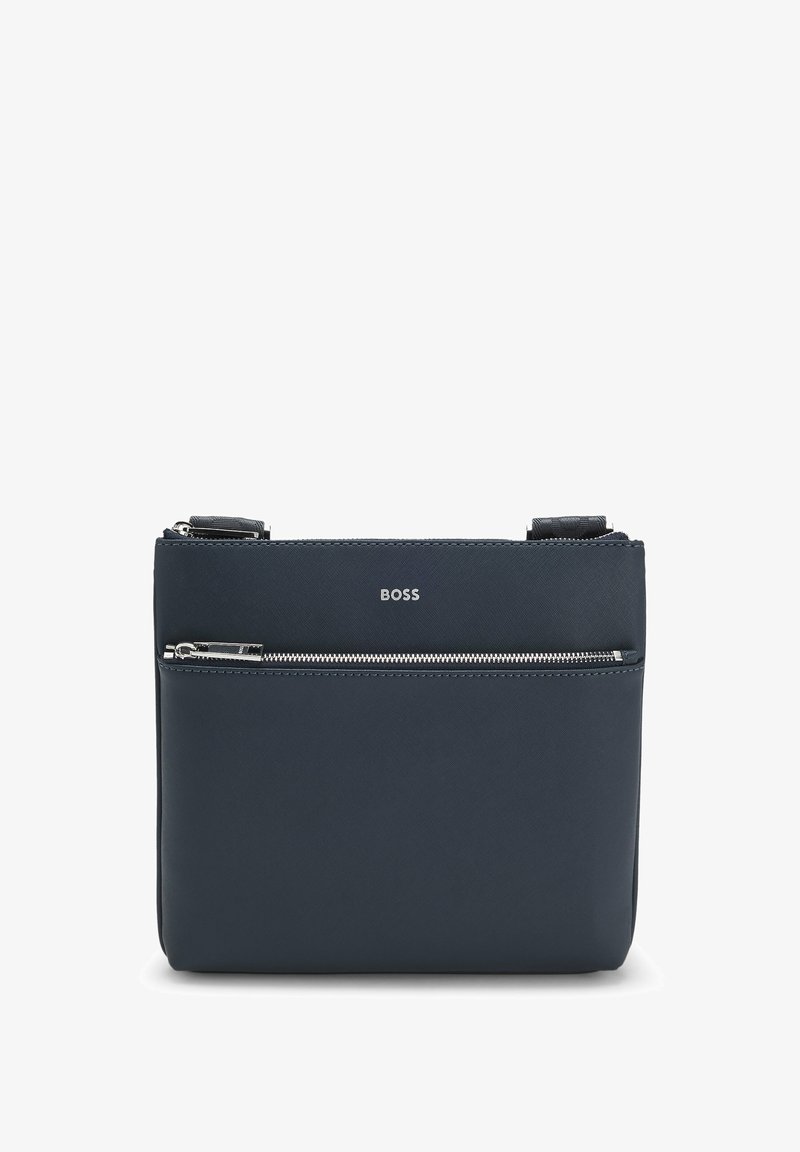 Granatowa skórzana torba na ramię, o prostokątnym kształcie, z przednią kieszenią na zamek, srebrnymi elementami oraz wytłoczonym logo na przodzie.