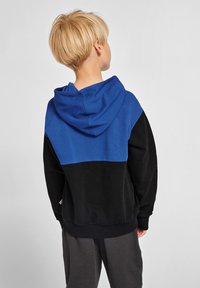 Hoodie z niebieską górną częścią i czarną dolną częścią. Miękka tkanina, luźny krój i kieszeń kangurza z przodu.